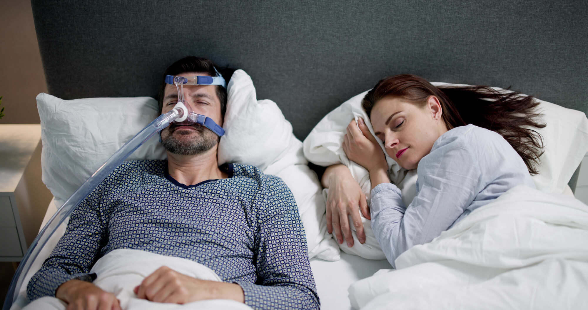 couple sleeping and one using a CPAP machine