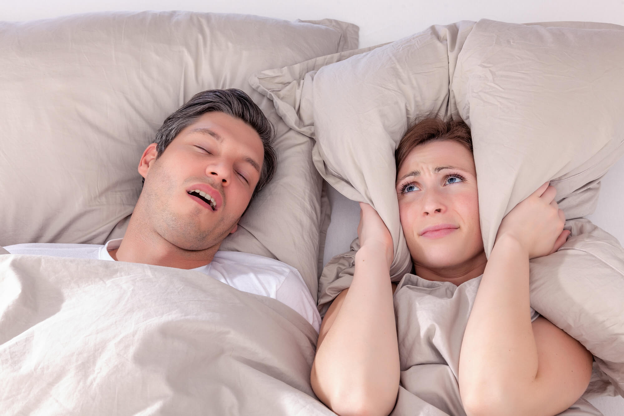 woman covering her ears because her partner is snoring